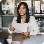 A businesswoman holds a sheet of paper and smiles at her client. 